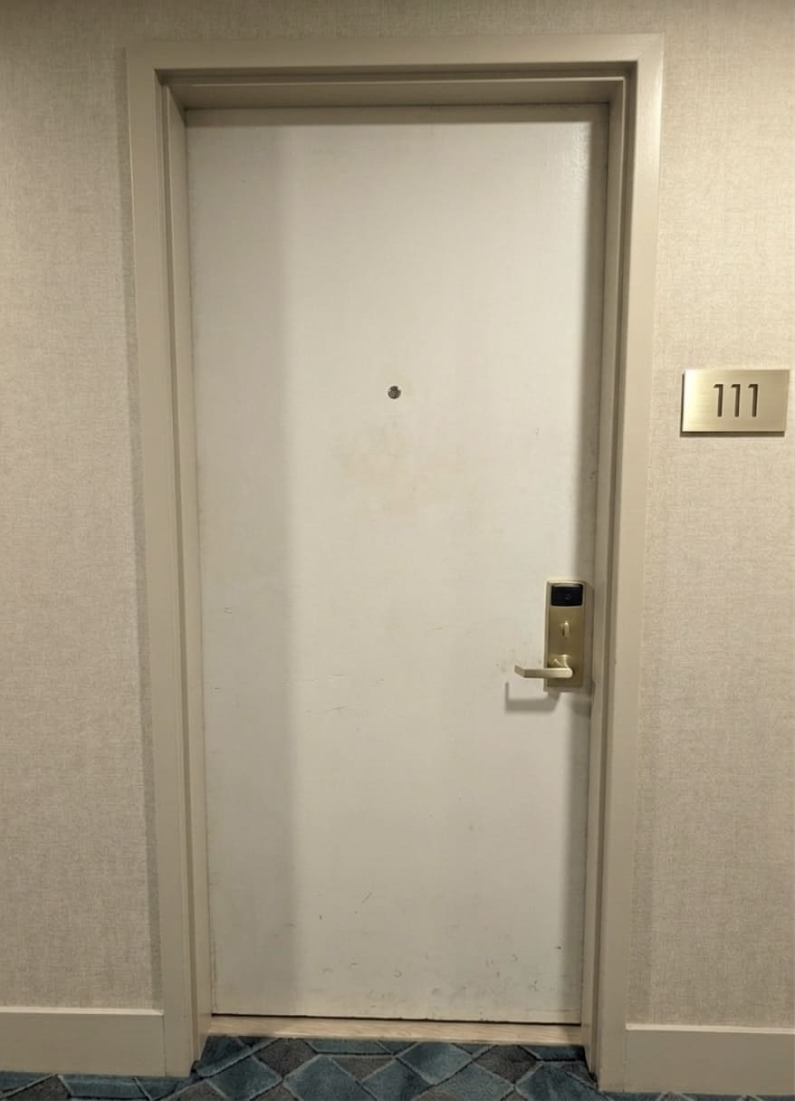 Before hotel corridor door upgrade showing a worn light-colored door