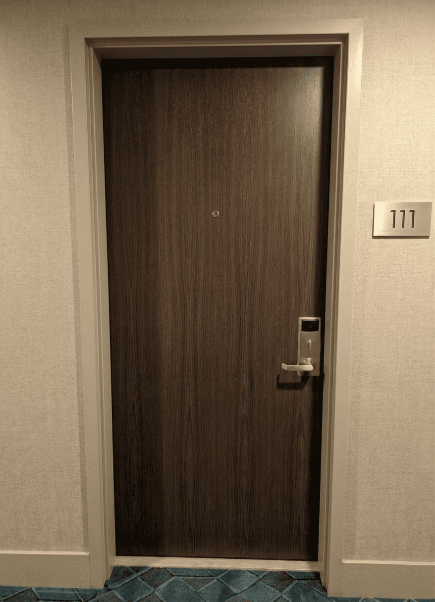 After hotel corridor door upgrade showing a premium dark wood finish